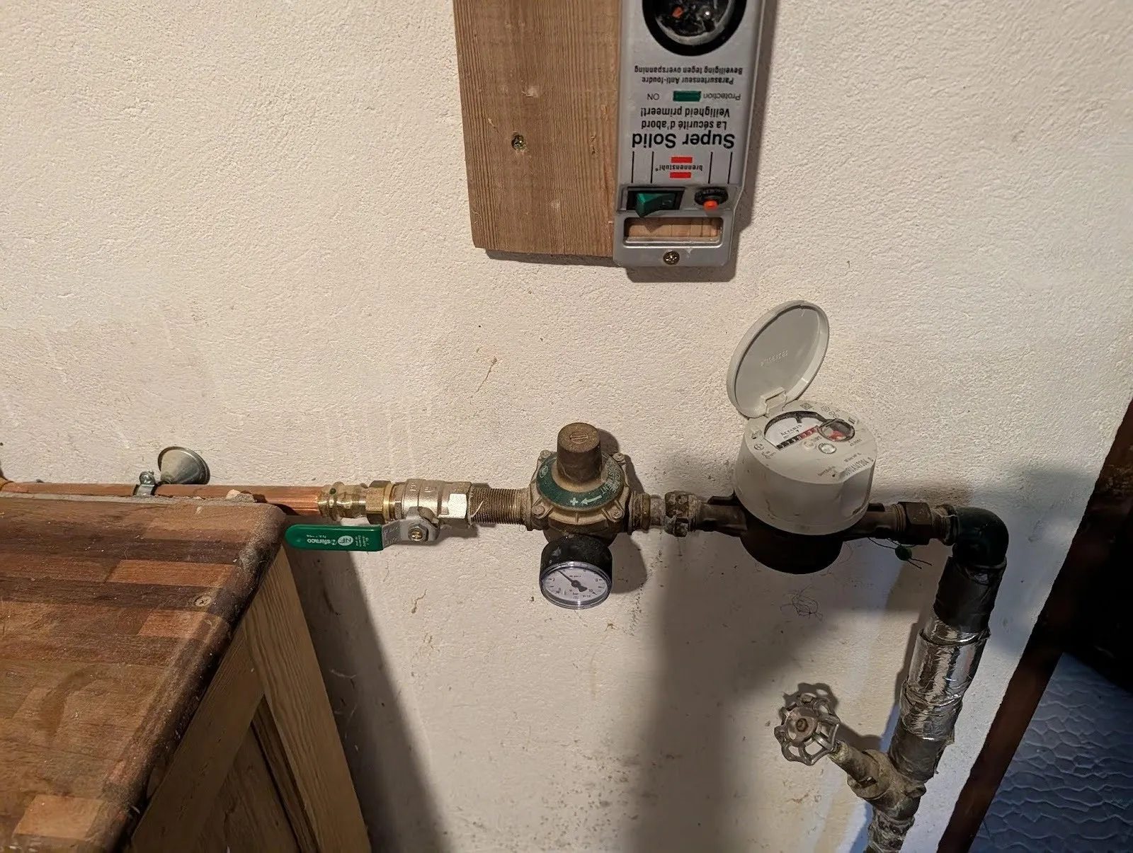 The main water valve and meter in the boiler room, next to the door to the garage